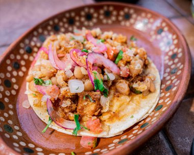 Lezzetli Meksika usulü chicharron ve kişniş, soğan ve domatesli taco, kil tabakta servis edilir..