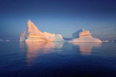 Kutup gecesinde batan güneşin ışınlarında yüzen buzullar