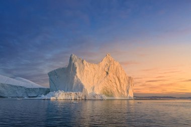 Kutup gecesinde batan güneşin ışınlarında yüzen buzullar