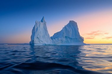 Kutup gecesinde batan güneşin ışınlarında yüzen buzullar
