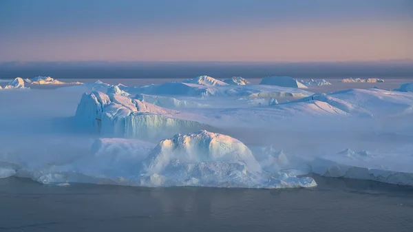 Kutup gecesinde batan güneşin ışınlarında yüzen buzullar — Stok fotoğraf