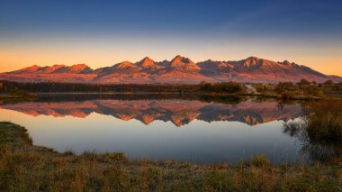 Yüksek Tatras, sonbaharda Slovakya 'da günbatımında göle yansıdı