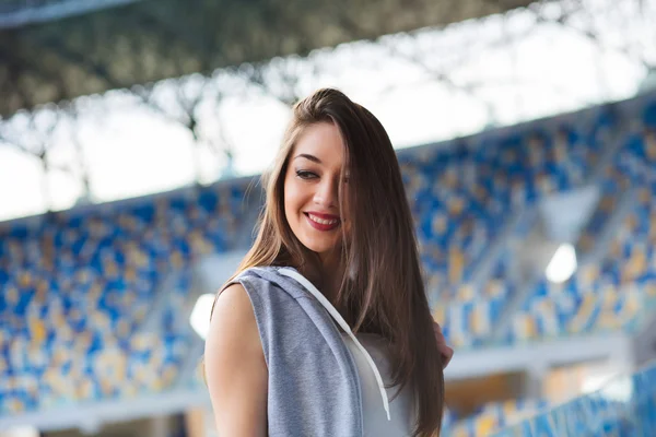 Szép sportos sportos lány rövidnadrág, ujjatlan ing közötti kék ülésekben egy stadion, este folyamán a szabadban nekirohanni Egyetem campus stadium — Stock Fotó