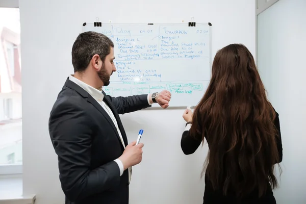 Jeunes gens d'affaires assis à une réunion, en utilisant le conseil — Photo