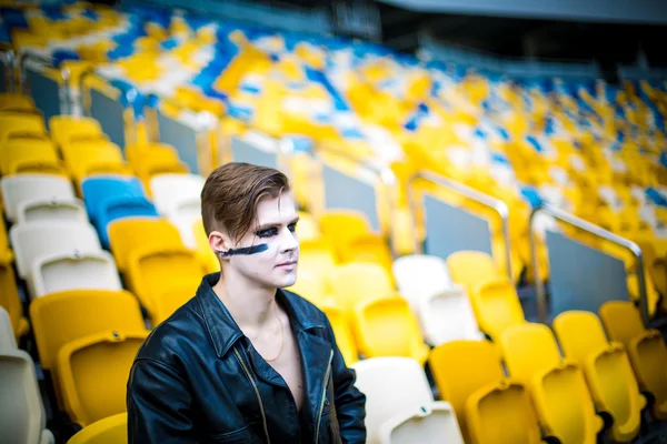 Moda relajada para los hombres en chaqueta de cuero posando mientras están sentados en el estadio — Foto de Stock