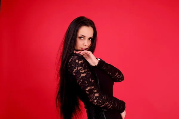 Giovane ragazza in un classico abito nero e scarpe nere su sfondo rosso — Foto Stock