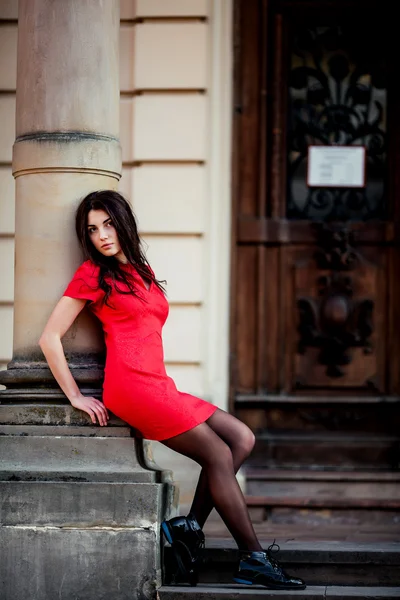 Attractive young beautiful woman in the antique style, sits in a red dress — Stock Photo, Image