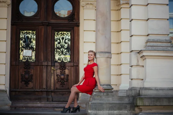 Bella ragazza bionda in un abito rosso con lunghi capelli sani, creando sullo sfondo della vecchia signora edificio, Lviv — Foto Stock