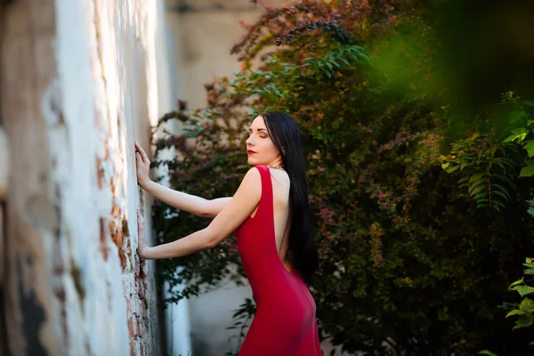 Mulher morena bonita em pé junto a uma parede de pedra em um verão da — Fotografia de Stock