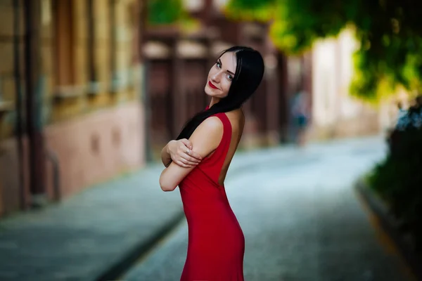 Street fashion concept: Ritratto di una bella giovane donna che indossa un abito rosso passeggiando per la città. Vecchio sfondo architettura — Foto Stock