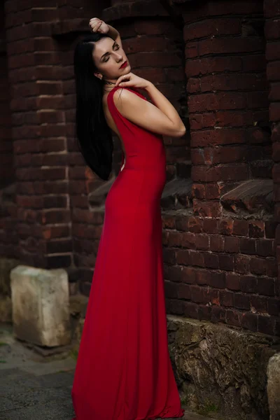 Hermosa joven posando sobre un fondo de edificios rojos — Foto de Stock