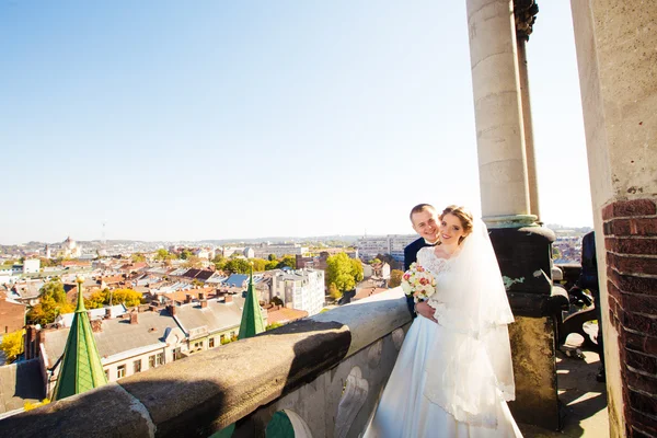 Gyönyörű esküvői pár ifjú állva erkély tartozik, kilátással a városra — Stock Fotó