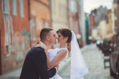 zarif damat güzel esmer gelini eski beyaz duvar arka plan üzerinde yukarı kaldırma