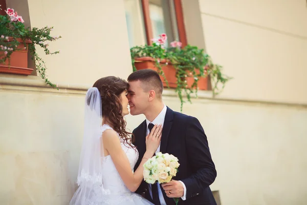 Séance photo de mariage. Mariée et marié marchant dans la ville. Couple marié embrassant et se regardant. Bouquet de maintien. Extérieur, corps entier — Photo