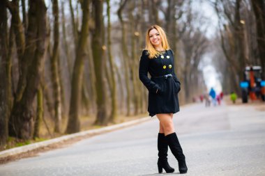 Sarı ve turuncu yaprak bir sürü sonbahar Park ince esmer genç güzel bir ceket uzun saçlı kız yürüyor