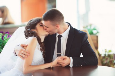 Evlilik çift aşık. Mavi elbiseli kafede otururken yakışıklı damat ile güzel gelin beyaz elbise ve peçe ve gelin buketi. Tam uzunlukta adam ve kız portresi. Düğün kavramı