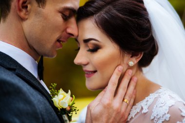 Arka planda çiçekli yanağında yakışıklı damat dokunmadan duygusal, romantik gelin