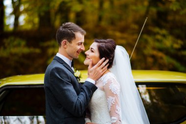 Arka planda çiçekli yanağında yakışıklı damat dokunmadan duygusal, romantik gelin