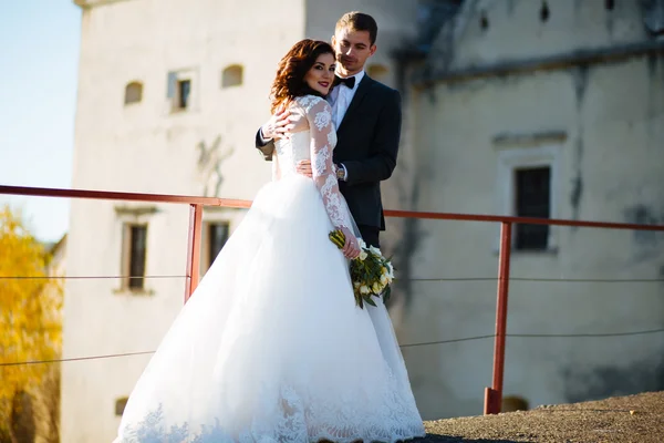 Gelukkig lachend jonggehuwden buiten wandelen, kussen en omhelzen op hun trouwdag — Stockfoto