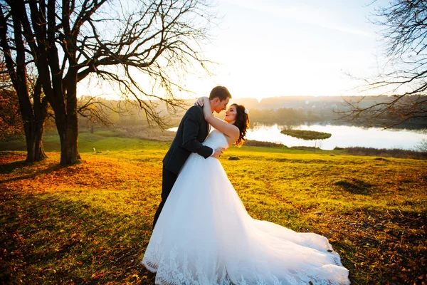 Joyeux marié beau et belle mariée étreinte sur le balcon au coucher du soleil gros plan — Photo