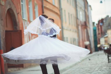 Damat nazik hareket ettirildiğinde gelin, onu tutarak onun kollarında ve tutkuyla öper, düğün fotoğraf güneşli bir kum renkli duvarlar arka plan üzerinde. Yeni evli çift Park, sokak tango dans.