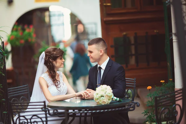 Casamento casal sentado no café ao ar livre ao pôr do sol — Fotografia de Stock