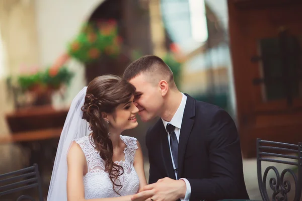 Fotografia de casamento. A noiva e o noivo sentados em um café, abraçando e sorrindo. Muito próximos um do outro . — Fotografia de Stock