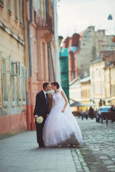 Ślubne zdjęcie fotografowania. Panna młoda i pan młody spaceru po mieście. Szuakm Ogarnięcie i patrząc na siebie. Trzymając bukiet. Odkryty, pełne ciała — Zdjęcie stockowe