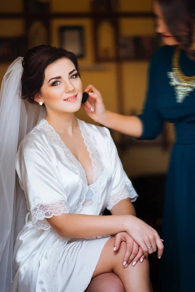Mooie bruid met make-up en krullend kapsel van het huwelijk. Stylist maakt make-up bruid op trouwdag. Schoonheid portret van een jonge vrouw op ochtend. — Stockfoto