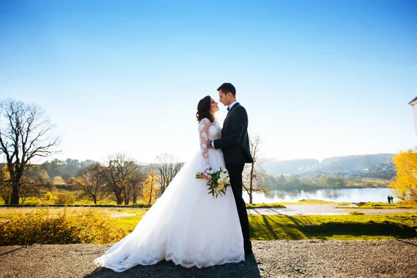 Belle mariée élégante heureuse avec marié élégant sur le fond de beaux arbres dans le parc d'automne — Photo