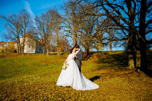 Novomanželé, líbání a usmívá se na jejich svatební den na procházku venku. Legrační nevěsta s kyticí. — Stock fotografie