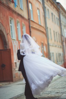 zarif damat güzel esmer gelini eski beyaz duvar arka plan üzerinde yukarı kaldırma