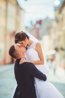 Fotoğraf çekim düğün. Gelin ve damat şehirde yürüyüş. Kucaklayan ve birbirine bakarak evli çift. Buket tutarak. Açık, tam vücut