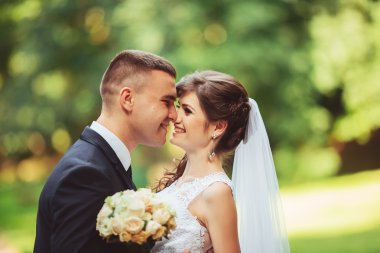 Güzel bir düğün çifti. Düğün gününde gelin ve damat bahar doğasında dışarıda yürüyor. Yeni evli çift yeşil bir parkı kucaklayan mutlu kadın ve erkek..