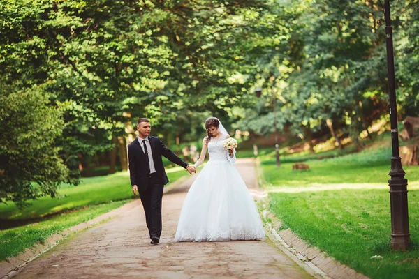 Mooie jonge gelukkig bruidspaar in park, outdoor, groene achtergrond. Nieuwe familie. — Stockfoto