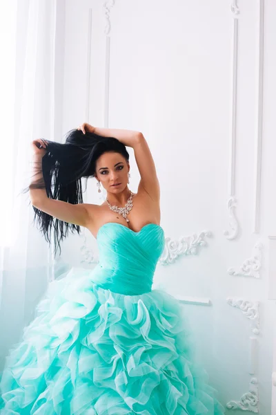 Studio fashion portrait of a beautiful young girl with dark hair, wearing a blue dress luxury zedeno — Stock Photo, Image