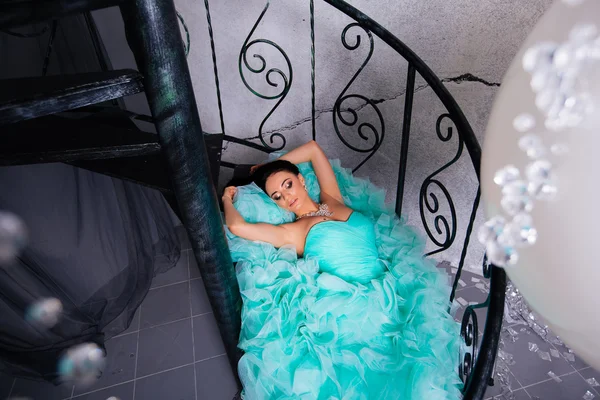 Hochmode. Emotionales Porträt der schönen sexy Brünette mit langen Haaren in einem grünen Kleid, auf der Treppe liegend — Stockfoto