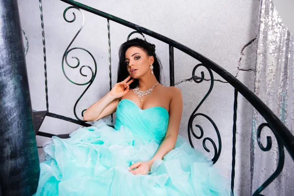 Schöne junge Frau sitzt auf der Treppe in einem Kleid, grübelnden Blick — Stockfoto