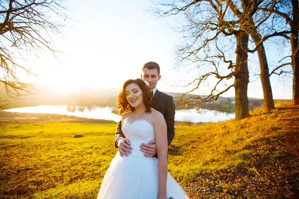 Belle mariée élégante heureuse avec marié élégant sur le fond de beaux arbres dans le parc d'automne — Photo
