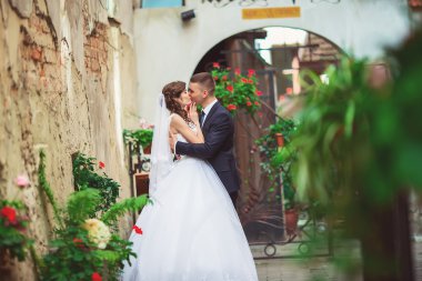 Fotoğraf çekim düğün. Gelin ve damat şehirde yürüyüş. Kucaklayan ve birbirine bakarak evli çift. Buket tutarak. Açık, tam vücut