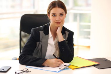 Gülümseyen kız evrakları dolduruyor, işadamı ofiste..