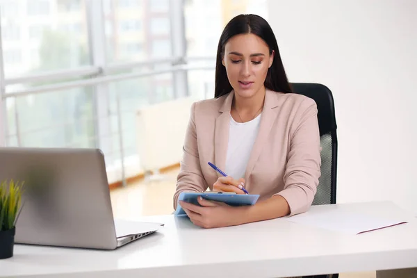 Young female content manager makes notes with a pen