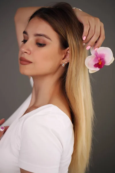 Schönheitsporträt. Schöne stilvolle Mädchen mit Orchidee-Blume. Perfekte Gesichtshaut. Gesundes Haar. — Stockfoto
