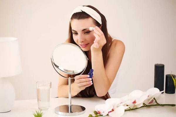 Wanita cantik menyentuh kulit halus di rumah di depan cermin — Stok Foto