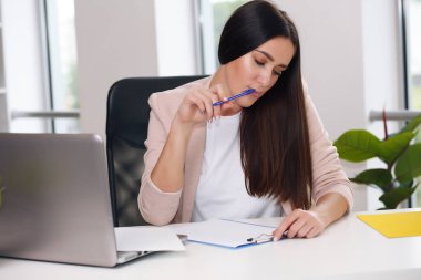 Ofiste dizüstü bilgisayarda oturan pembe ceketli bir iş adamı.