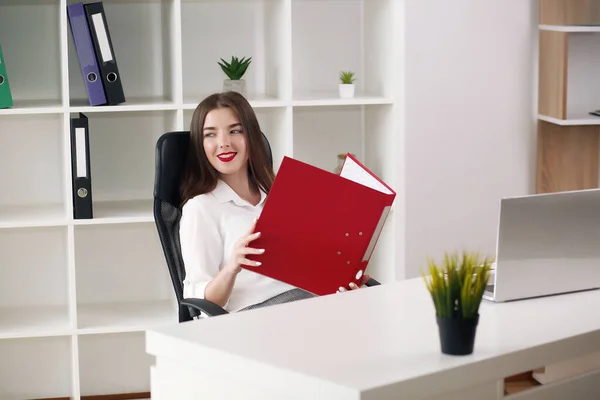 Modern ofiste dizüstü bilgisayarla oturan beyaz gömlekli genç bir iş kadını portresi. — Stok fotoğraf