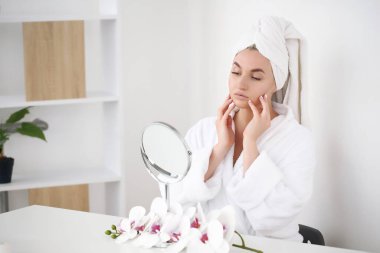 bornoz ve havlu banyo aynaya bakarak kafasına güzel gülümseyen genç kadın.