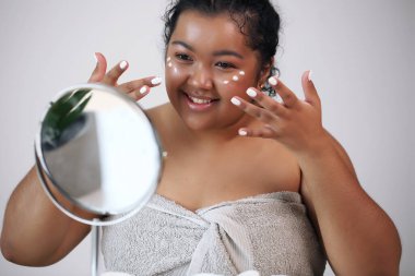 Çekici bir genç kadının yüzüne krem sürerken yakın plan portresi..