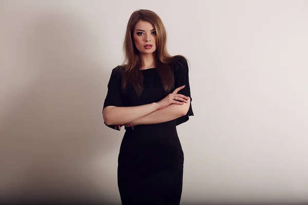 Joven morena en vestido negro posando sobre fondo gris — Foto de Stock