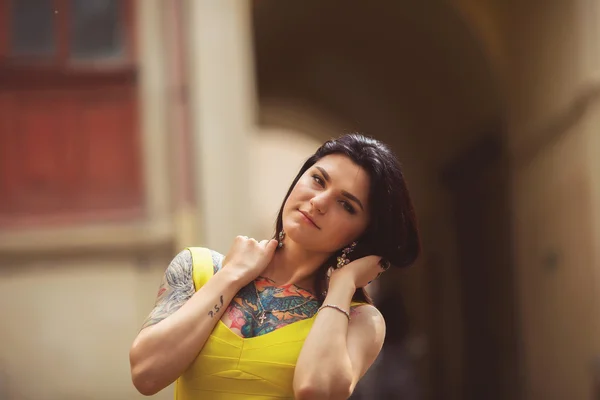 Una bella donna in abito giallo, tatuaggi, posa per foto — Foto Stock
